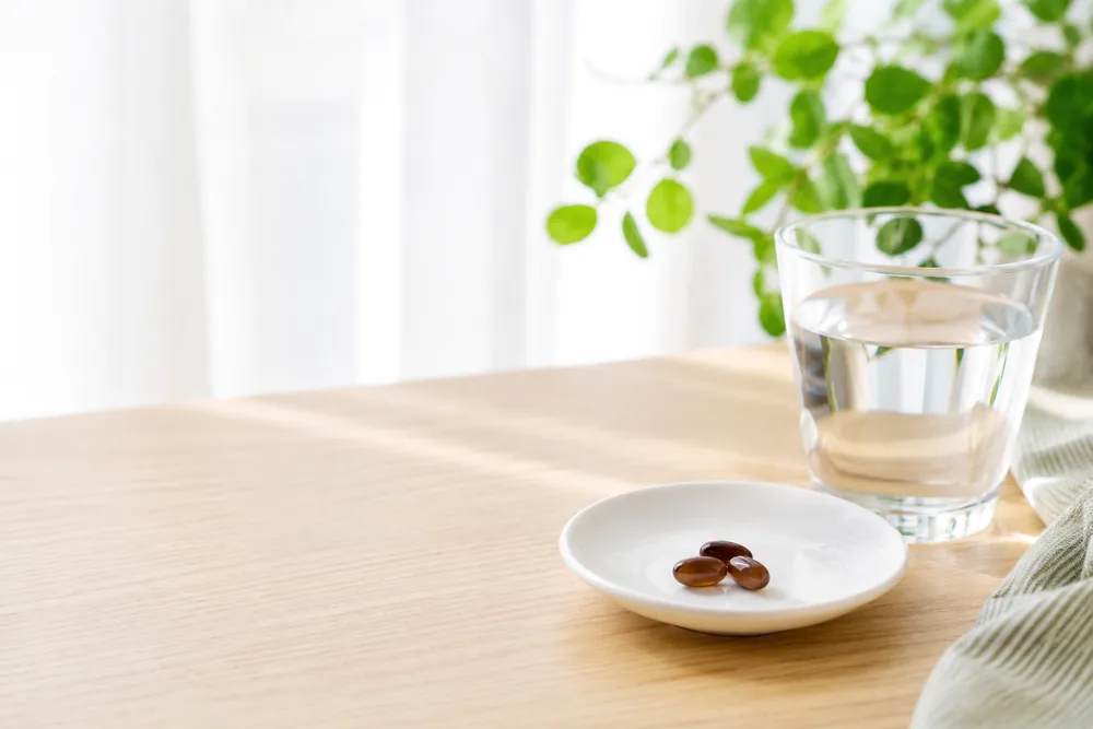 水と3粒のカプセルが置かれた朝のテーブル